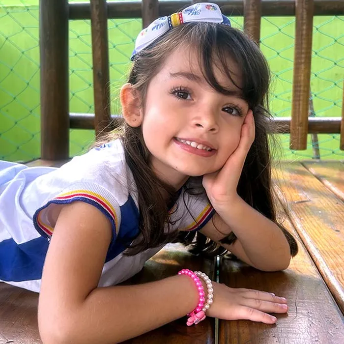 Aluna do Colégio Vencer sorrindo com o rosto apoiado na mão